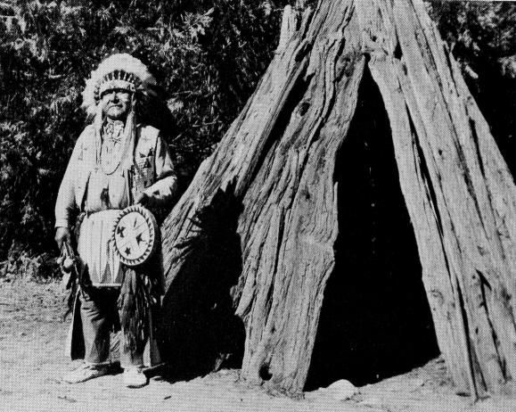 Chris Brown (Chief Leeme) beside cedar bark house in Yosemite National Park