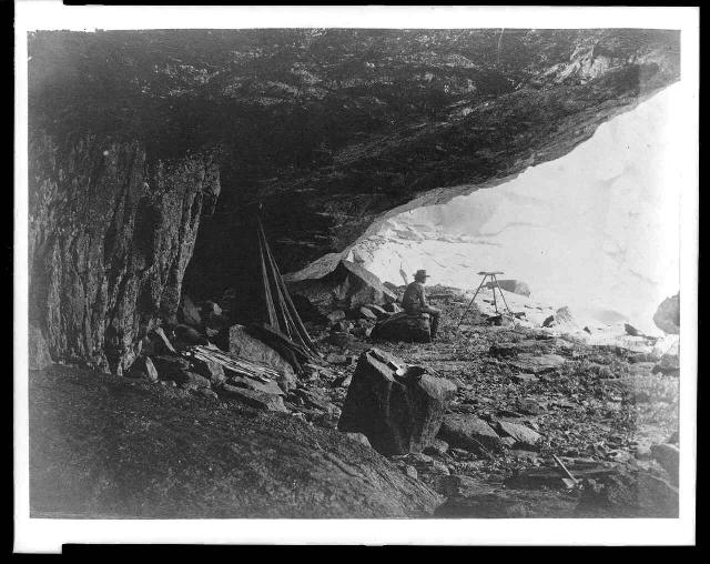 Man seated beneath rock formation at the Upper Yosemite Fall