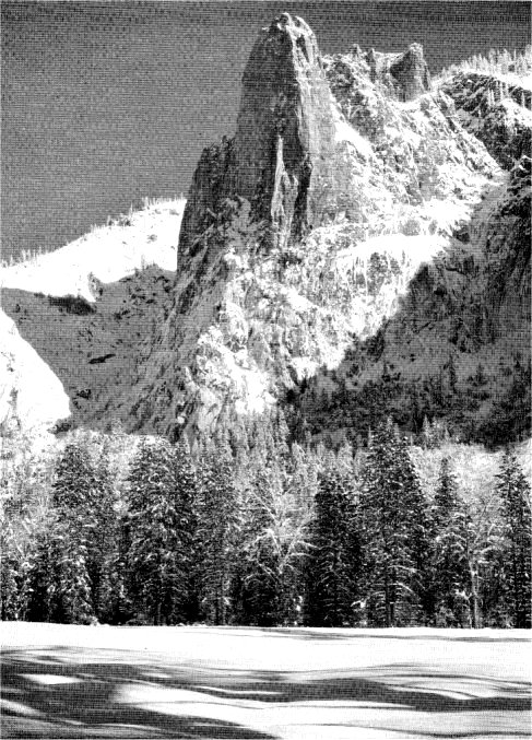 Against a sky of cobalt blue, Sentinel Rock raises its turrets above a world of dazzling white. By Ansel Adams